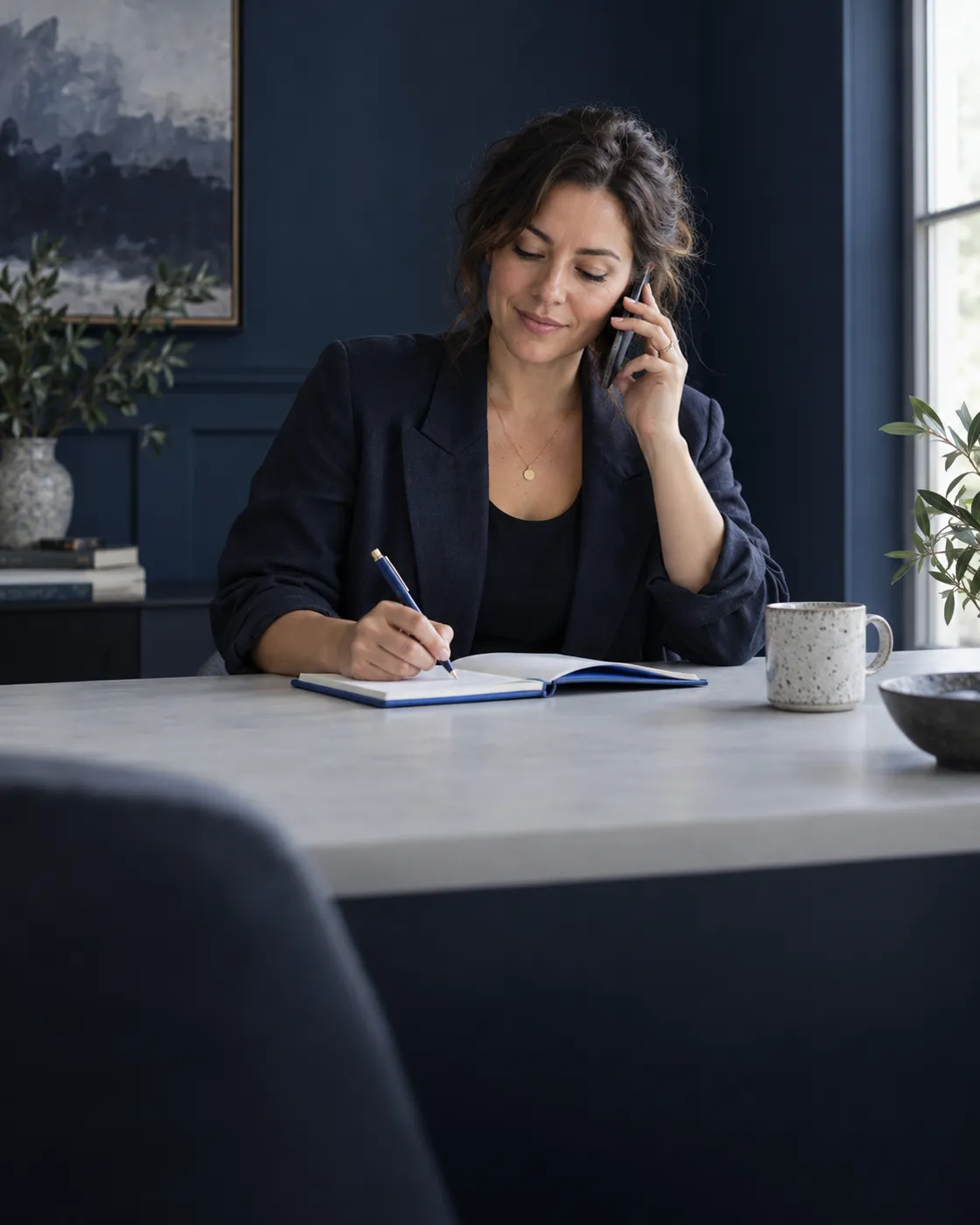 A business owner on the phone, taking notes in a cobalt notebook